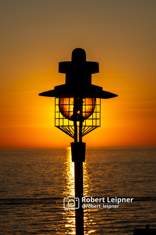 orange-rötlicher Sonnenuntergang hinter einer Straßenlaterne in Rovinj