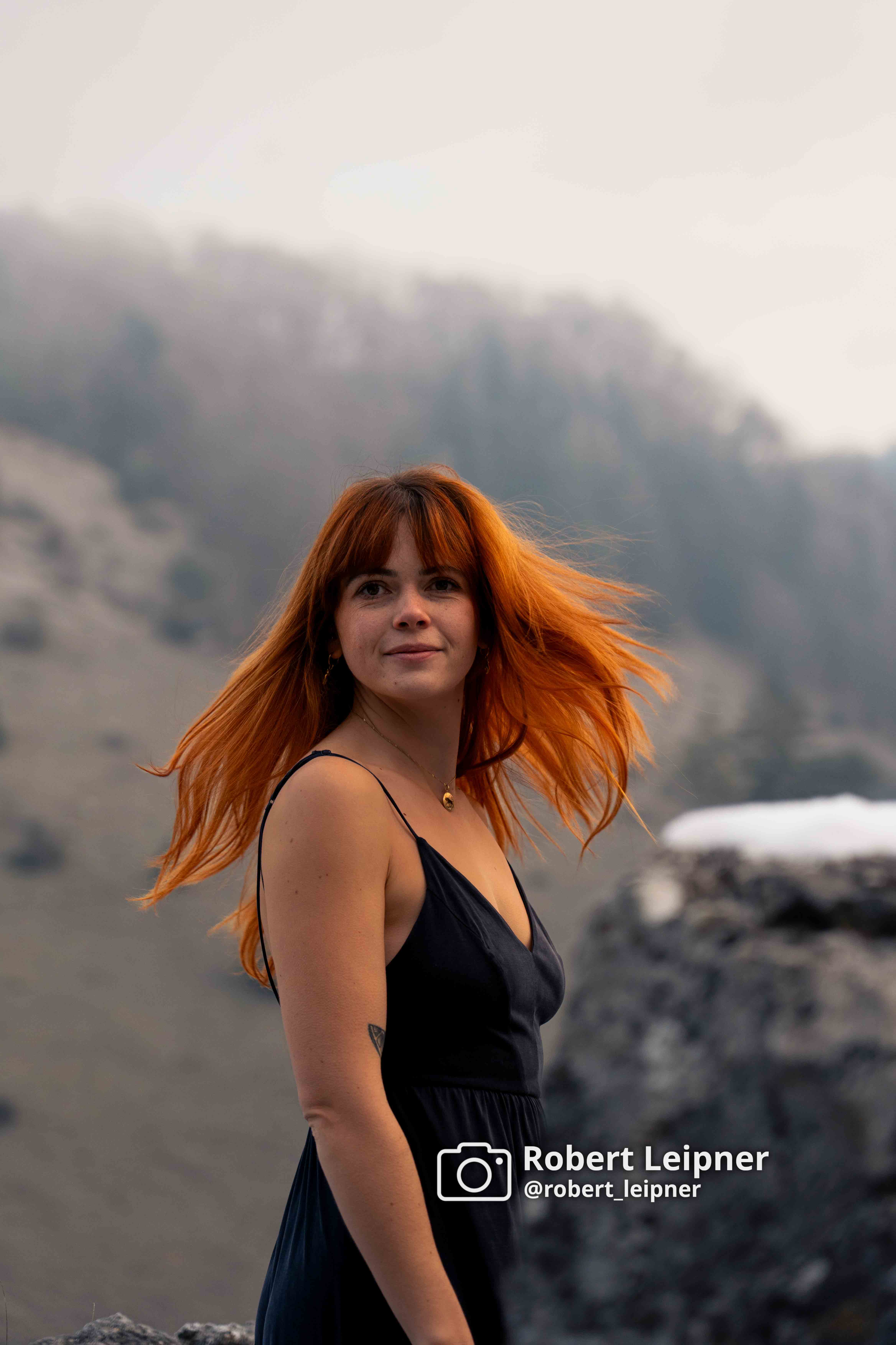 Model mit roten Haaren und schwarzem Kleid im Winter